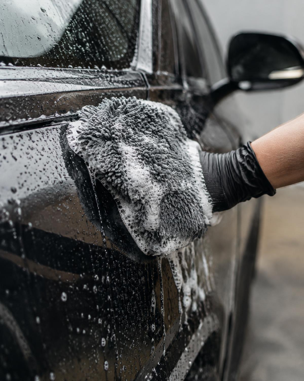 A car receiving a careful hand wash with clean wash media during a mobile detailing service